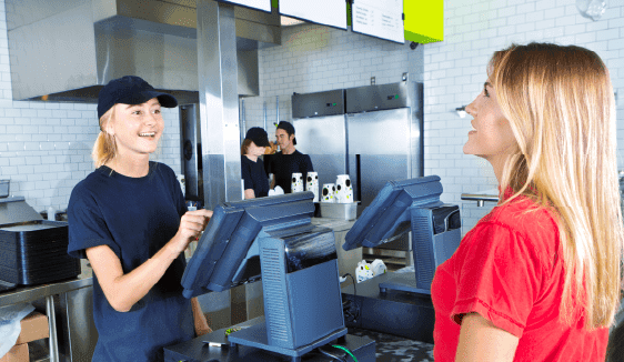 Image of a fast-food restaurant with a customer using a mobile phone nearby.