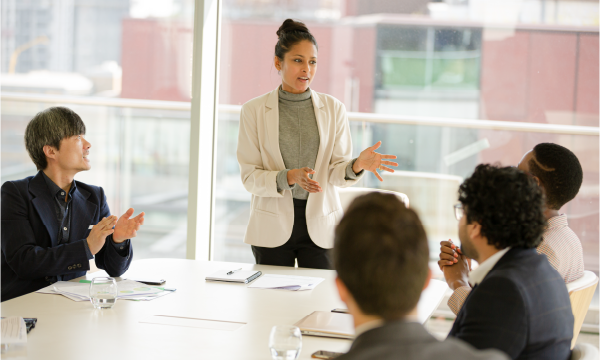 Woman standing in front of co-workers leading a meeting