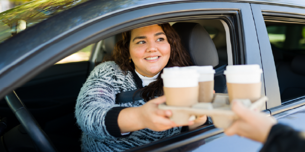 Photo of a woman receiving coffee through her car window
