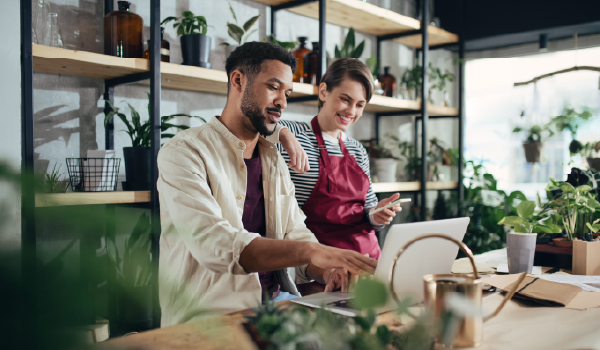 Two people inside of a plant store looking at their laptop and phone