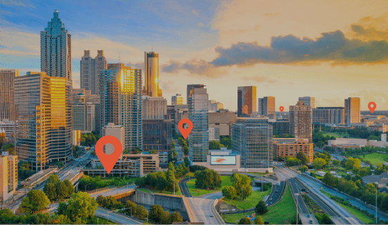City skyline at sunset with map pins marking multiple storefront locations, representing multi-location franchise marketing across urban neighborhoods.