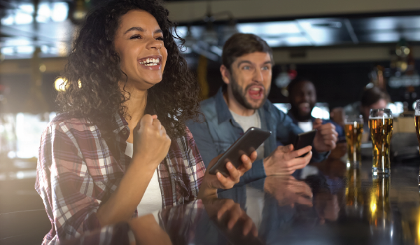 Two people in a sports bar with their mobile devices