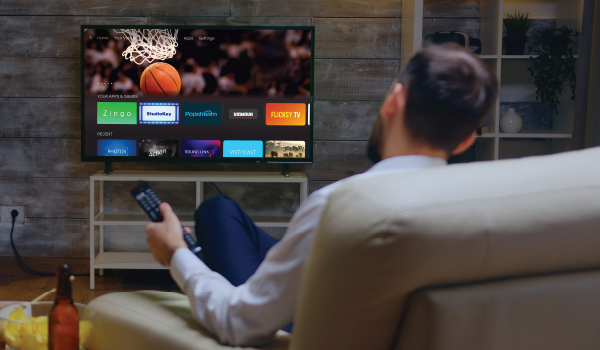 A person with a TV remote in their hand looking at their smart TV