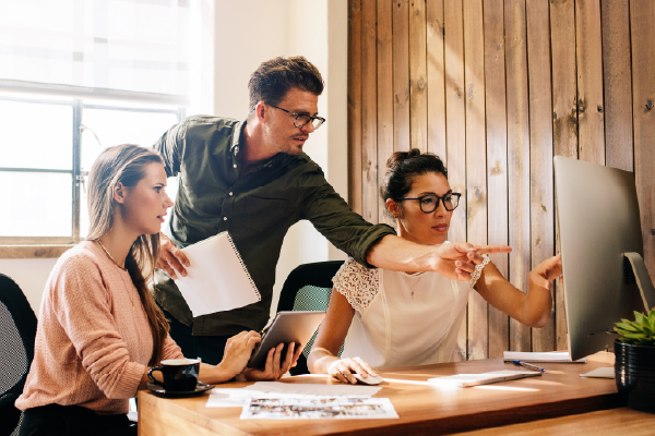 Team of coworkers, pointing at a screen or looking at growing projections based on their native success.